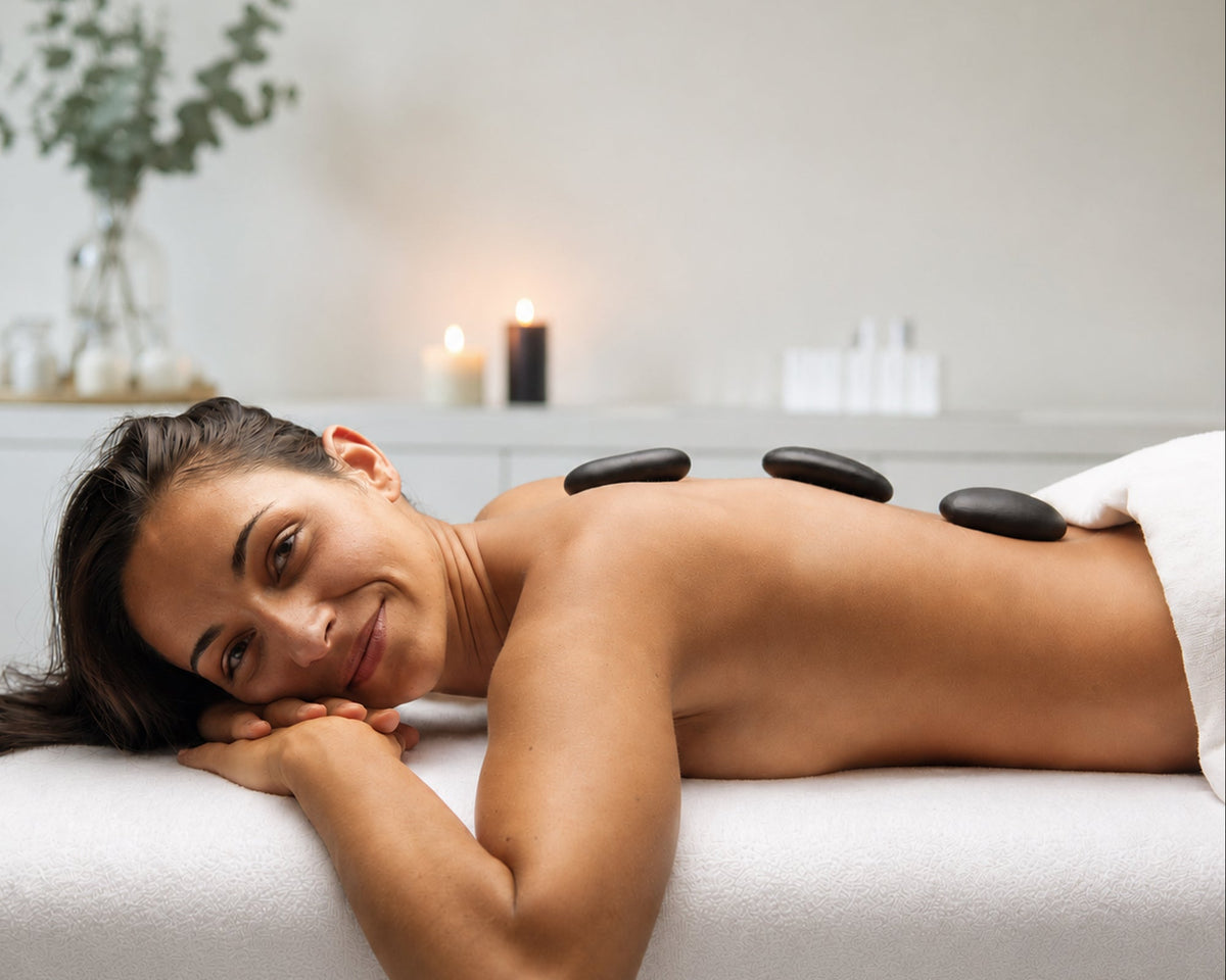 Frau entspannt bei einer Ganzkörpermassage mit warmen Basaltsteinen auf dem Rücken